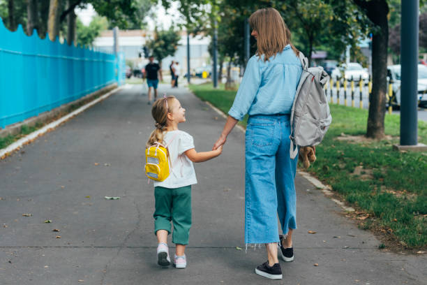Mother walking together with her daughter, holding her hand
