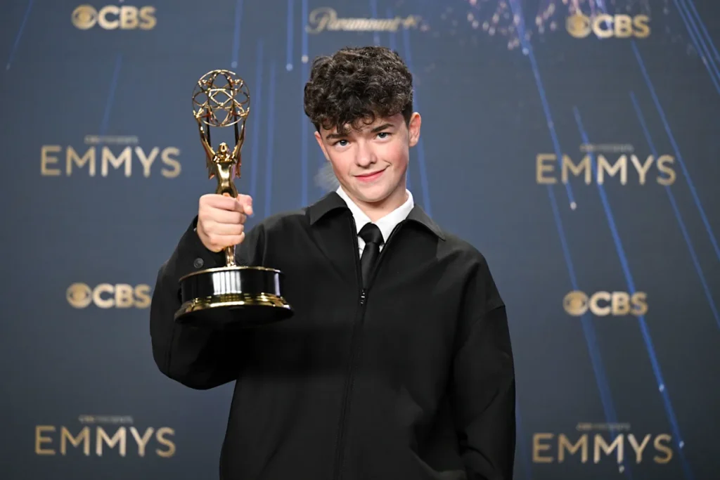Owen Cooper holding his Emmy award while smiling on stage